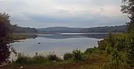 A color photograph of a lake under a blue sky.