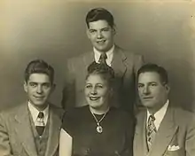 A portrait of a teenage Silvers standing behind seated family members