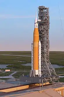 Artist's rendering of the Space Launch System Block 1 sitting on LC-39B with the Orion spacecraft at sunrise.