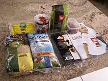 An assortment of foods on a worktop. They are: tofu, wheat miso, bancha tea, umeboshi prumes brown rice, sea salt and nori.