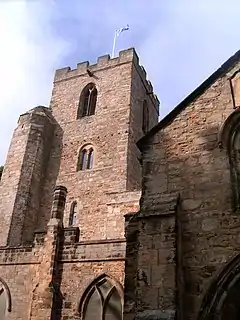 A stone church building with a tower. On the top of the tower, a Saltire flag flies on a pole.