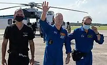 Douglas Hurley waves to onlookers as he boards a plane at Naval Air Station Pensacola.