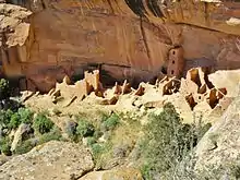 A color picture of a large sandstone ruin under an alcove