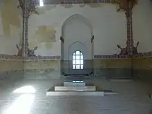 Photograph of the interior of a mausoleum showing a window and decorated tile on the walls