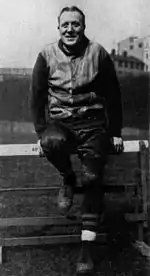 Jock Sutherland sitting on a track and field hurdle.