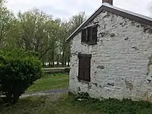 side of old white building with woods and river in background