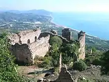 Ruined stone walls on a high hill looking out over a shoreline below