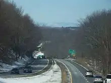 Looking downslope along a divided highway in winter with mountains in the distance