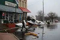 A photo of the Jamestown Cafe with a large pile of debris on the damp street in front of it. The pile is about 20' by 10' and perhaps 7' high at its peak. Much of the debris is wood and building sheet (perhaps steel?)