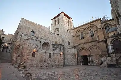 Modern photograph of a large stone building with a tower and a gate on it.