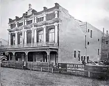 black and white image of a stone and brick theatre two or three story building showing a very decorative front and a very plain side