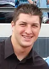 Headshot of caucasian male with dark hair in black buttoned shirt