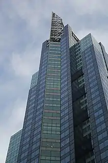 The "prow" of the building, as seen from Broadway. The prow is a trapezoidal glass structure that protrudes from the facade. There is a steel spire above it.