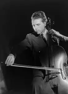  clean-shaven, slim white man with aquiline features, seen profile playing the cello