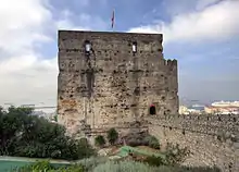 A square tower with gardens in the foreground and a connecting wall on the right—hand side