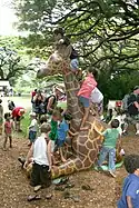 Children playing on a giraffe statue at the zoo