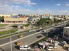 View of the central market area of Urgench from the fifth floor of the Hamkor Bank building. In the background, the blue and white building of the "Gipermarket", the largest shopping centre in Urgench.