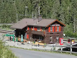 Two-story wooden building with gabled roof next to double-track railway line