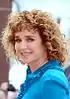 Valeria Golino at the 2016 Cannes Film Festival with curly hair, looking to the front, wearing a blue shirt and smiling