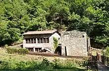 Photograph of the last mill in operation in the valley, Chez Lyonnet. The mill is visible in the foreground, with the forest in the background.