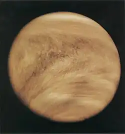 Light brown clouds wrap around a planet, as seen from space.