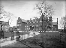 A large three-storey building behind a wrought-iron fence