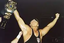 Wrestler Owen Hart holds up the "Winged Eagle" championship belt