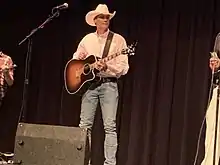 Singer Wade Hayes, holding a guitar while onstage.