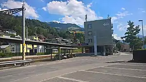 Rectangular four-story building next to canopy-covered platforms