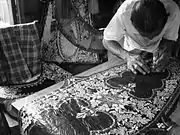 A wau-maker in his workshop. Design details in his wau are made by cutting various layers of coloured paper. The cutting is done spontaneously.