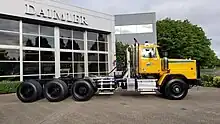 Yellow day cab Western Star 6900. Tri-drive rear axles with single steer axle, and equipped with a fifth wheel.