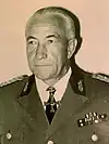 A black-and-white photograph of a man wearing a black military uniform, peaked cap and a neck order in shape of an Iron Cross.