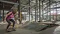 Indoor skatepark with one skateboarder riding a ramp