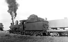 A black and white photo of a steam train blowing steam