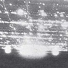 A grayscale image, covered in glowing white spots. The image is split into two unequal parts. The bottom, smaller part, which takes approximately a third of the image, is slightly tilted. It uses a darker shade of gray, and has a few bigger white spots on top of it. Above it is the bigger, lighter part, placed at an angle to the viewer. It is covered with smaller white spots, arranged in a grid pattern.