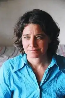 Cohen headshot, she is shown from the chest up, she is looking straight into the camera. She has light blue eyes, and graying brown hair, cut just above the shoulder. She is wearing a bright blue collared shirt.