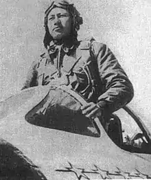 A Chinese man in a flight suit standing in the cockpit of an aircraft.