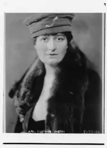 A white woman wearing a fabric hat and a fur stole